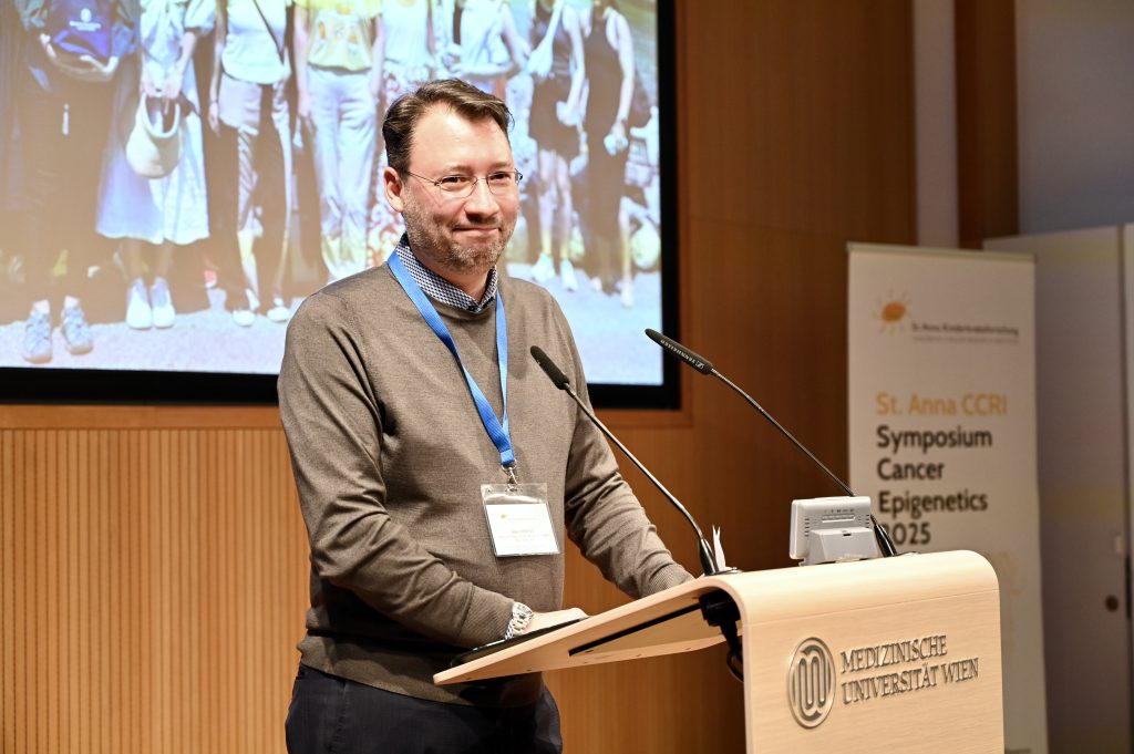 The scientist Alex Kentsis stands behind a speakers desk presenting his research