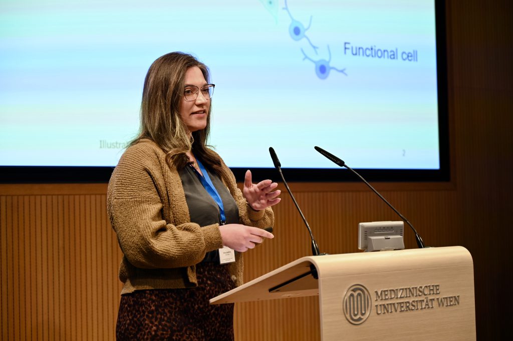 The scientist Polina Kameneva stands behind a speakers desk presenting her research